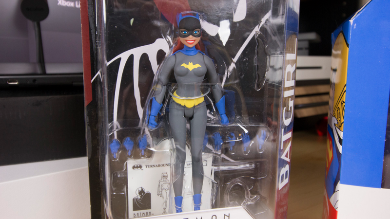 Batgirl, also coming out next month, is framed by hands in her package.